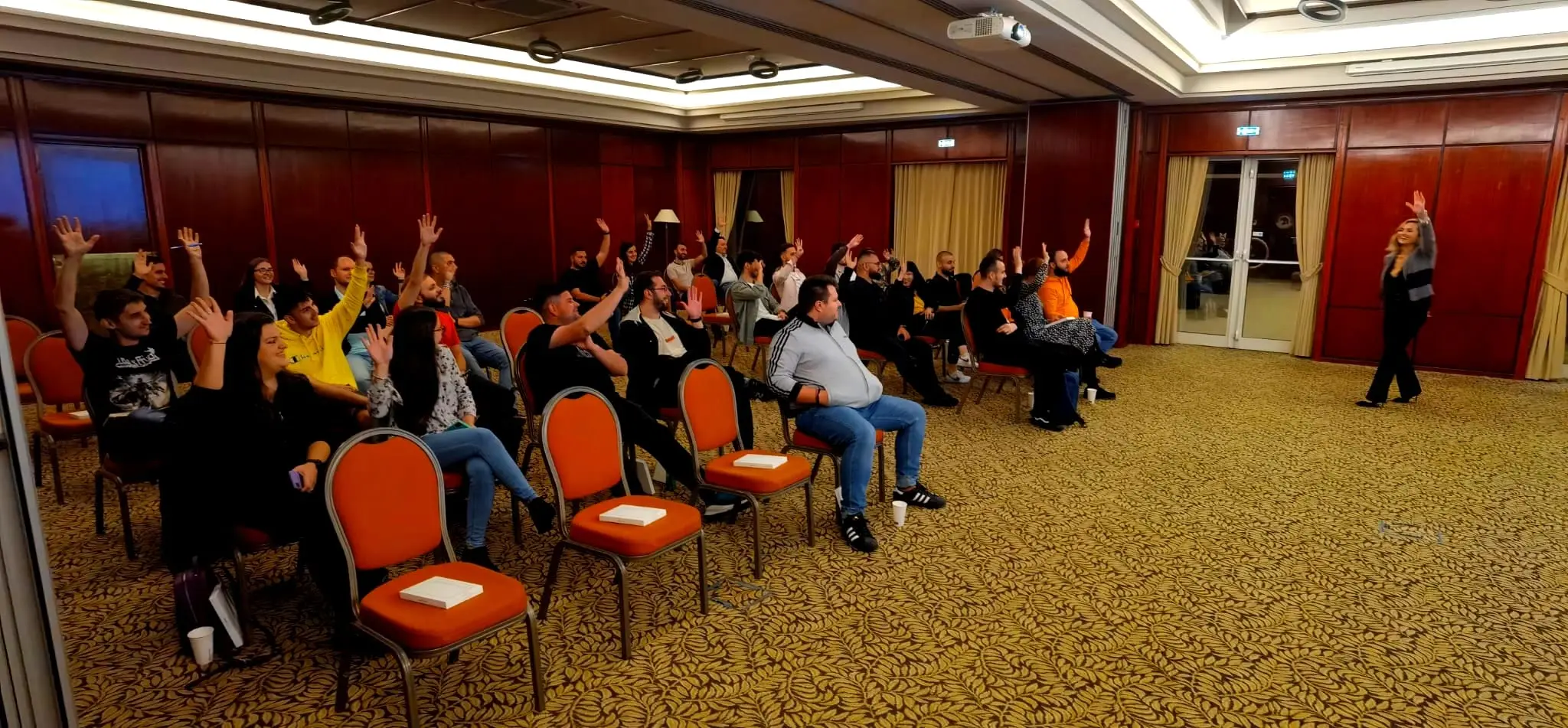 Participanți la un training NAL Achieve Limitless, ridicând mâinile într-o sesiune interactivă